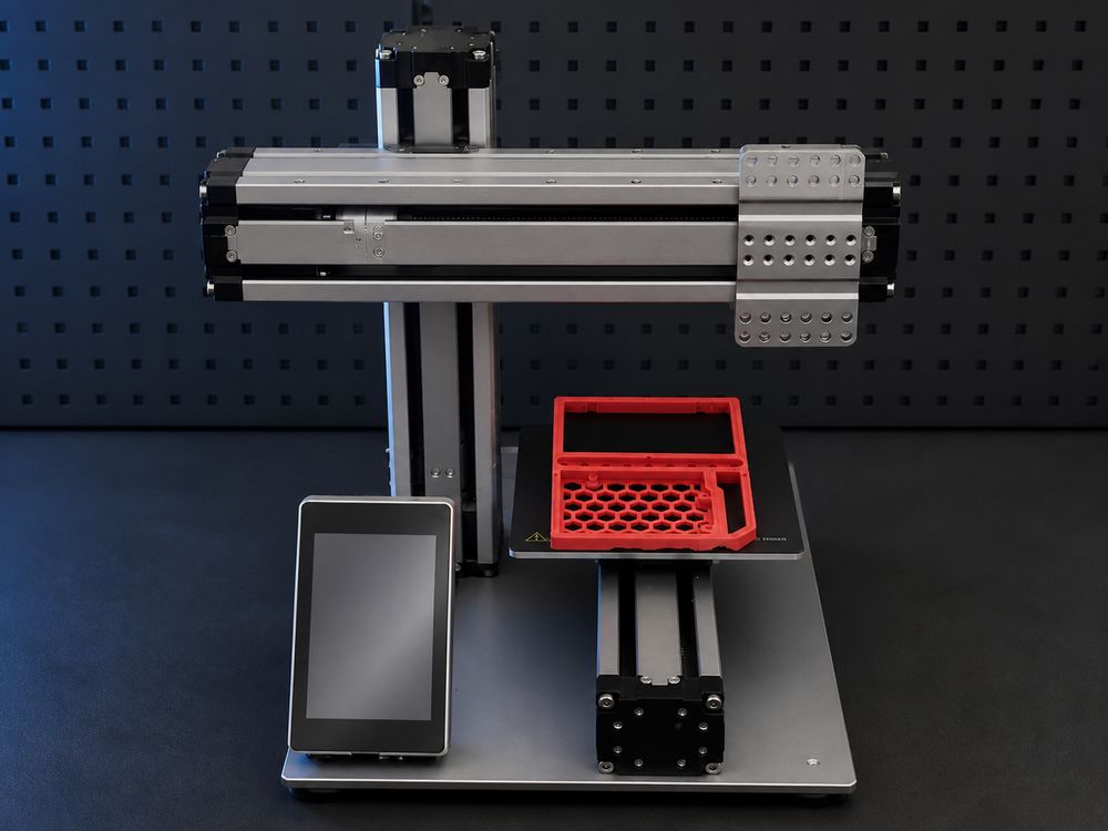 CNC and 3D-printing rig with a freshly printed red part on the bed